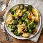 Crispy Air Fryer Broccoli and Cauliflower served on a white plate with lemon zest and parmesan cheese.