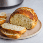 “Freshly baked Air Fryer Bread with golden crust and fluffy interior, resting on a cooling rack beside a butter dish—perfect homemade loaf made in the air fryer.”